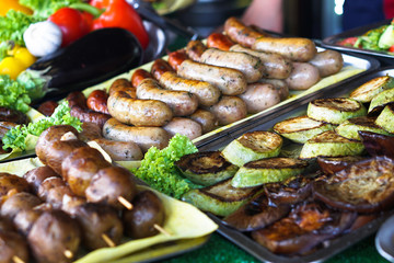 Dinner table with meat grill, roast new potatoes, vegetables, salads, sauces, snacks and lemonadeá Grilled sausage, mushrooms. Stock Photo