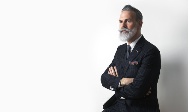 Portrait of bearded attractive gentleman wearing trendy suit over empty white background. Copy Paste text space.