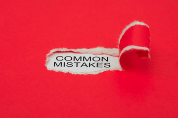 Torn red paper revealing the word. COMMON MISTAKES concept.