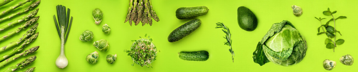 Grünes Gemüse breites flaches Laienkonzept. Microgreens, Rosenkohl, Spargel, Rosmarin, Avocado, Zwiebel, Kohl und Gurke auf grünem Hintergrund, Ansicht von oben