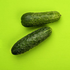 Cucumber on green background, top view.