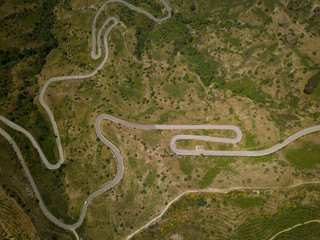 Aerial view of a mountain route with curves near to Etna volcano, Sicily, Italy. Ruined building and car.