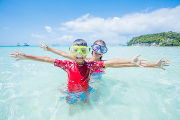 Two happy kids in diving masks having fun on the beach