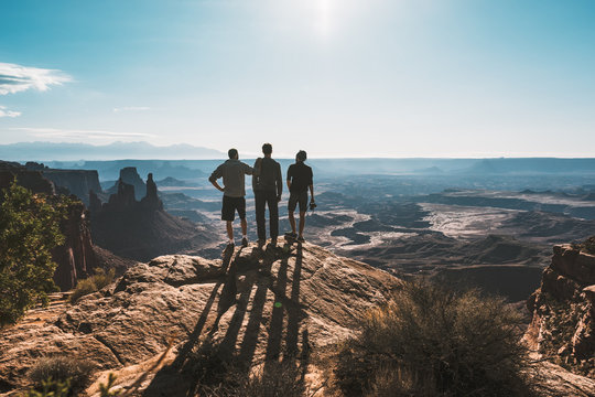 Group Of Three Young Men Admiring Magnificent View Of Canyonlands, Utah, USA.