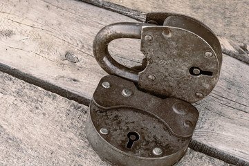 An old rusty padlock on a wooden background, toned in sepia-copper