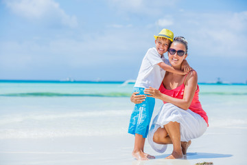 Happy family resting at beach in summer. Mother with boy resting on the beach. Young mother and her adorable little son on beach vacation