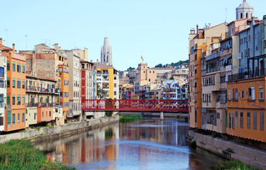 Naklejka na ściany i meble Colorful houses on both sides of the river Onyar. Red bridge. Beautiful town of Girona, Catalonia, Spain.