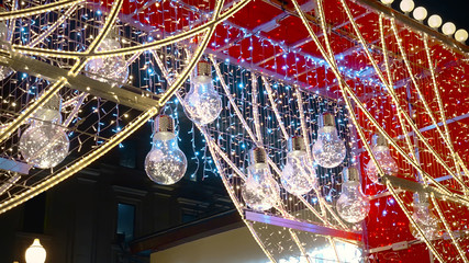 Winter New Year street decorations, light bulbs and lanterns shining at late night.
