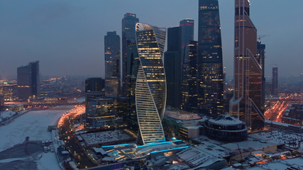 Late evening aerial shot of Moscow-city business towers with illuminated windows and Bagration...