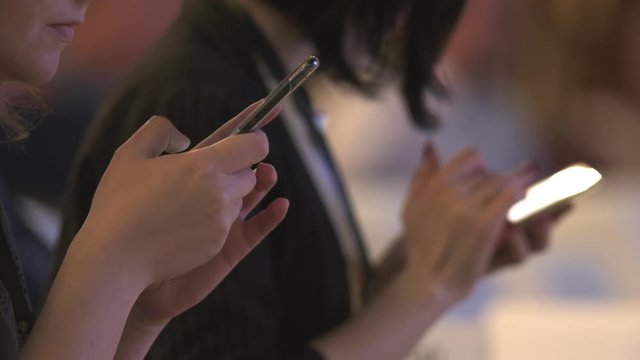 Hands of women writing on their phones at a conference