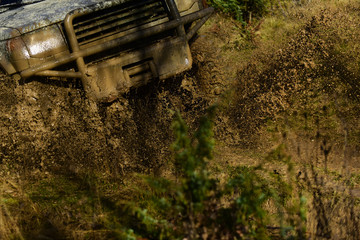 SUV on dirty forest road. Front side of vehicle covered with mud and dirt splash. Off road racing, force and extreme entertainment concept