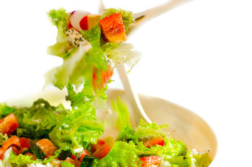 bowl of salad with vegetables and greens on wooden table
