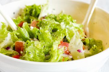 bowl of salad with vegetables and greens on wooden table