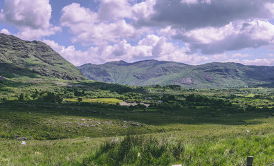 Fototapeta na wymiar The green fields and mountains as seen from Healy Pass, a 12 km route worth of hairpin turns winding through the borderlands of County Cork and County Kerry in Ireland