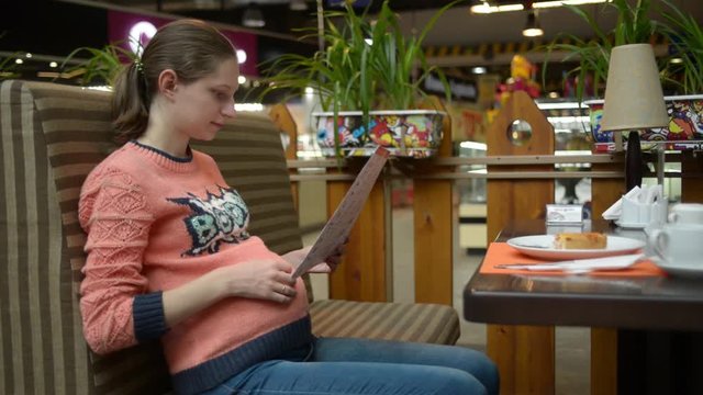 Pregnant woman eating cake at the mall cafe