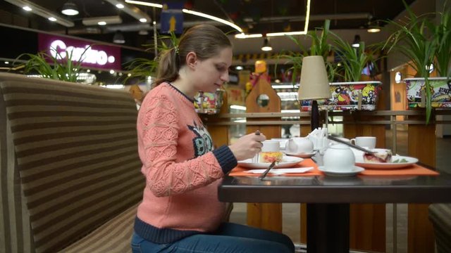 Pregnant woman eating cake at the mall cafe