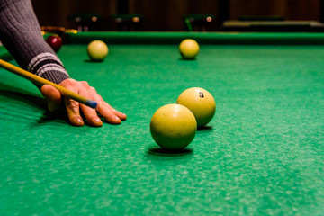 Player arm with the cue and balls on the green cloth. Russian billiard