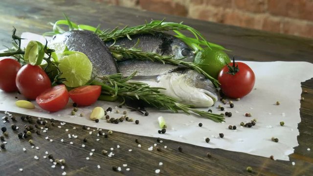 Ingredients for cooking fish. Fresh sea bass, green onions, lime, garlic cloves, rosemary, seasoning. 4K