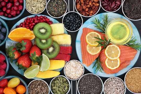 Health food for a healthy heart with fresh vegetables, fruit, nuts, seeds, pulses, grains, cereals, herbs and olive oil. High in omega 3 fatty acid, antioxidants, anthocyanins, minerals and vitamins.