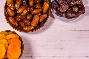 Date fruits and dried apricots on wooden table. Top view