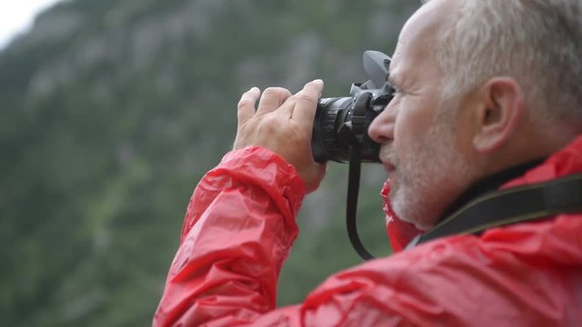 Alps. Male photographer taking pictures against the background of mountains