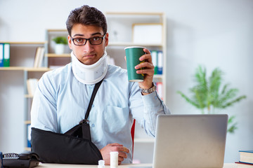 Businessman with broken arm working in office