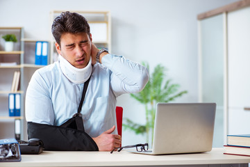 Businessman with broken arm working in office