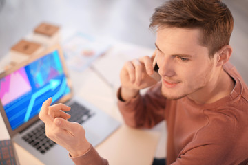 Young man talking on phone while working indoors