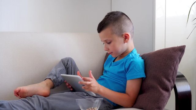 Cute boy relaxing while using tablet on sofa