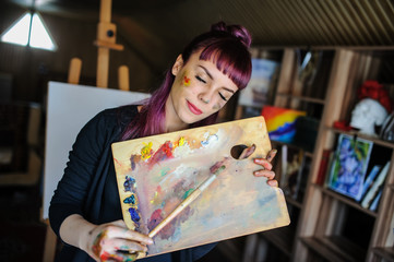 portrait of beautiful female artist with purple hair and dirty hands