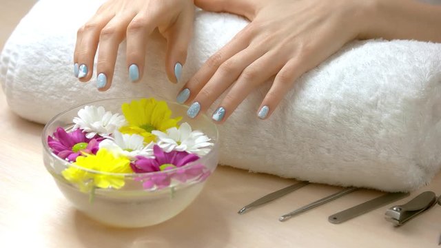 Female hands receiving spa treatment. Female manicured hands on towel. Womans hands with winter manicure is getting spa procedure. Hands and nails spa treatment.