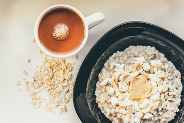 Homemade oatmeal with honey, peanut butter, peanut, flax seeds and cottage cheese on wooden background. Healthy breakfast.