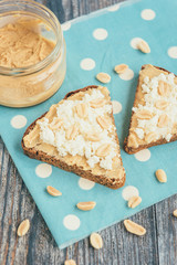 Bread with peanut butter, cottage cheese and peanut on wooden background. Healthy breakfast or snack.
