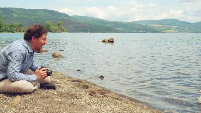 Man in front of lake in vacation taking pictures to nature and animals