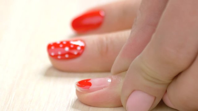Nail design by beautician close up. The process of painting a heart on nail, speed up motion. Woman receiving nail design in beauty studio.