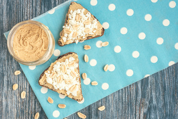 Bread with peanut butter, cottage cheese and peanut on wooden background. Healthy breakfast or snack.