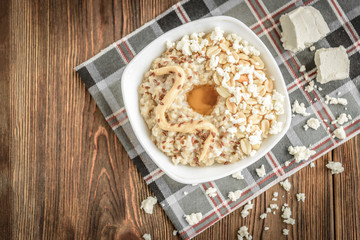 Homemade oatmeal with honey, peanut butter, peanut, flax seeds and cottage cheese on wooden background. Healthy breakfast.