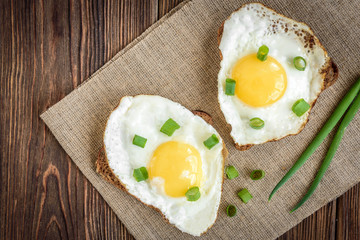 Toast with fried eggs and spring green onion on dark wooden background. Healthy breakfast, lunch, snack or dinner.