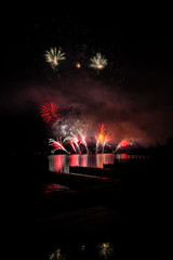 Beautiful colorful fireworks display on celebration night Celebration fireworks over the river with cityscape soft focus background at night scene