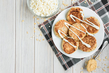 Oat cottage cheese pancakes with sour cream and peanut butter on white wooden background. Healthy breakfast, snack or diner.