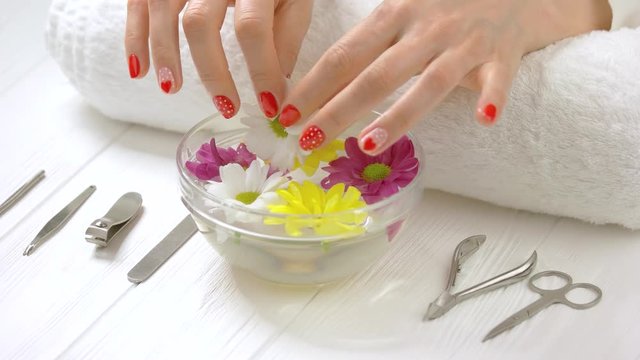 Woman hands in spa salon. Well-groomed female hands with beautiful manicure and gentle flower from aroma bath. Woman hands receiving spa procedure.