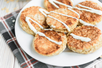 Oat cottage cheese pancakes with sour cream and peanut butter on white wooden background. Healthy breakfast, snack or diner.