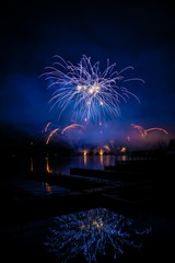 Beautiful colorful fireworks display on celebration night Celebration fireworks over the river with cityscape soft focus background at night scene