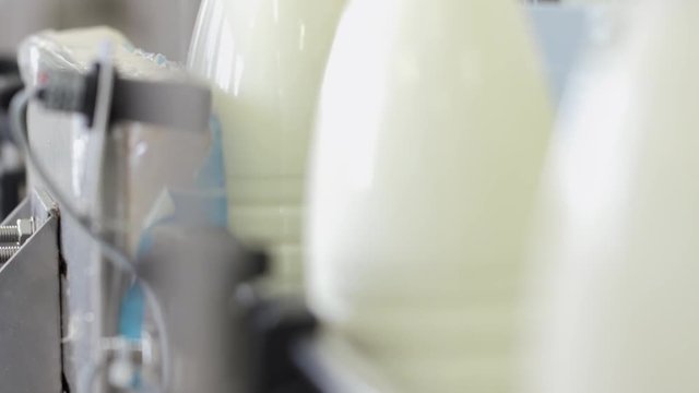 Factory milk making process. Close up packing milk plastic bottles. Label milk bottles in slow motion