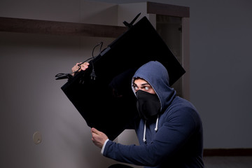 Burglar thief stealing tv from apartment house