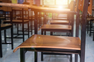 Lecture room or School empty classroom with desks chair iron wood for studying lessons in high school Thailand, interior of secondary education no kid teacher or young student with light flare