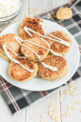 Oat cottage cheese pancakes with sour cream and peanut butter on white wooden background. Healthy breakfast, snack or diner.