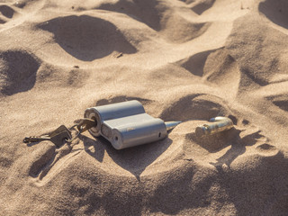 padlock with inserted keys on the sand