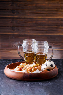 Picture of two mugs of beer and hot dogs on wooden tray