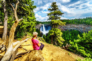 Senior woman enjoying the view of Helmcken Falls in Wells Gray Provincial park British Columbia, Canada with the falls at peak volume during spring snow melt